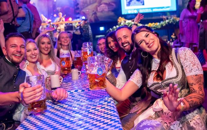 feiernde Gruppe in Tracht am Biertisch mit Masskrügen beim Europa Park Oktoberfest