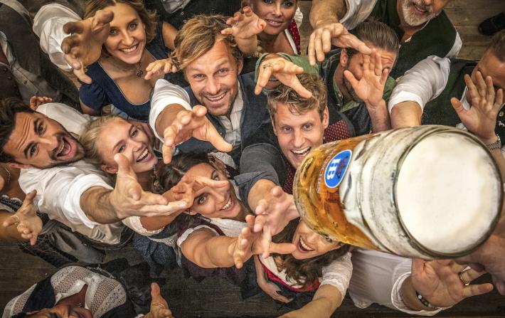 oktoberfest people reaching at beer mug