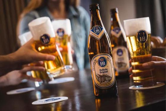 Hofbräu Original anstoßen Flasche Biergenuss München golden mit Schaumkrone