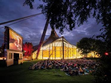 Open-Air Kino Leinwand und Liegestühle mit Olympiastadion und Olympiahalle im Hintergrund